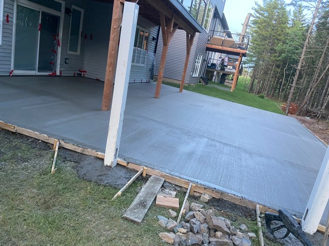 Broom-finish concrete patio wrapping around deck posts by A2Z Creteworks